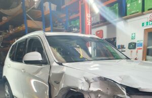 The Environmental Role of Modern Car Breakers Front-end damaged white BMW SUV inside a car breakers dismantling facility